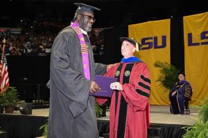 Legenda NBA Shaquille O'Neal tersenyum mengenakan toga saat wisuda S2 di Louisiana State University