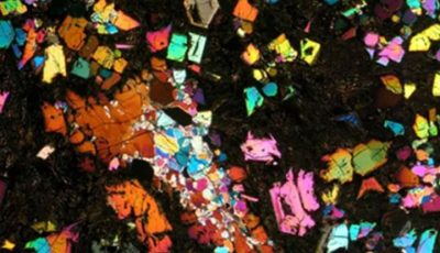 Irisan tipis sampel meteorit langka NWA 12774 jenis angrite di bawah pencahayaan mikroskop cahaya terpolarisasi silang