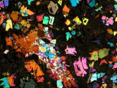 Irisan tipis sampel meteorit langka NWA 12774 jenis angrite di bawah pencahayaan mikroskop cahaya terpolarisasi silang