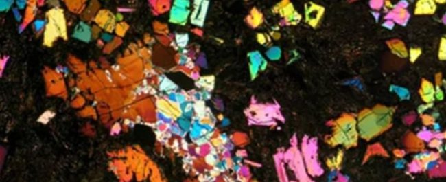 Irisan tipis sampel meteorit langka NWA 12774 jenis angrite di bawah pencahayaan mikroskop cahaya terpolarisasi silang